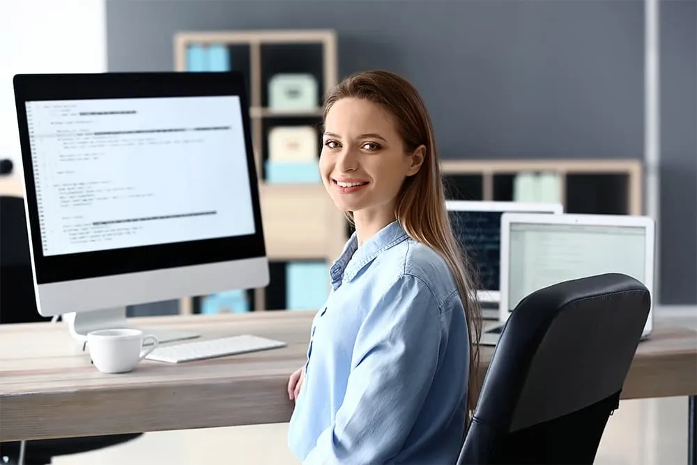 Junge Frau sitzt in Bluse vor PC