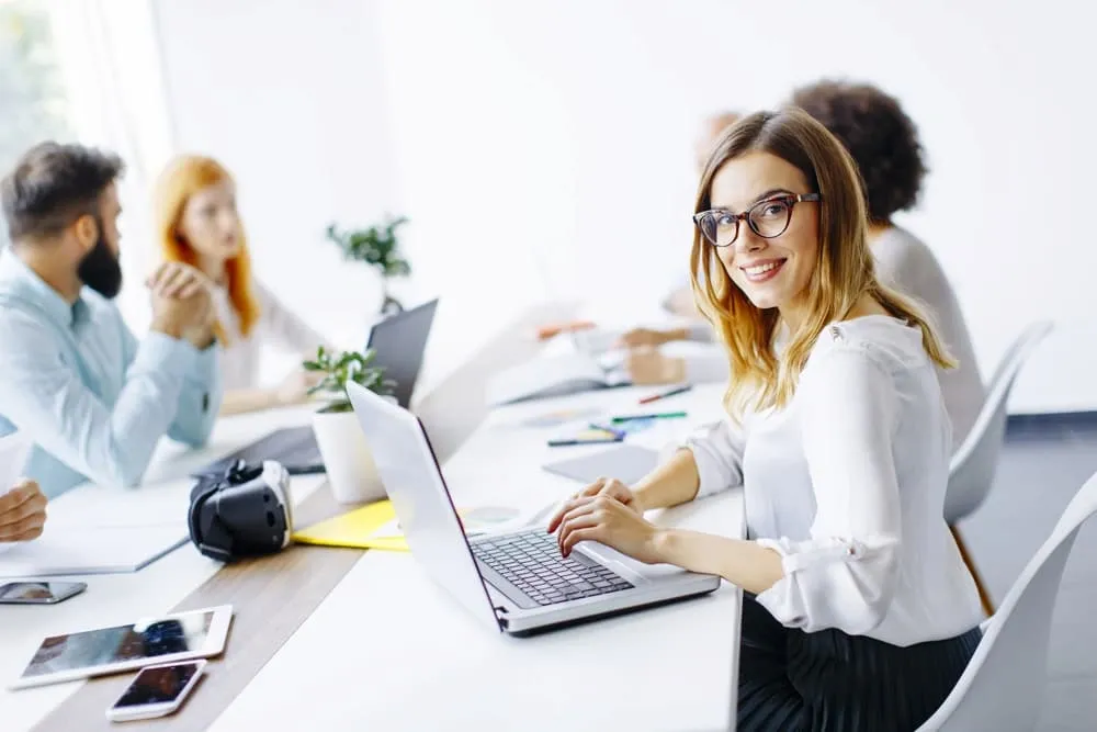 Junge Frau in Businesskleidung sitzend an Laptop