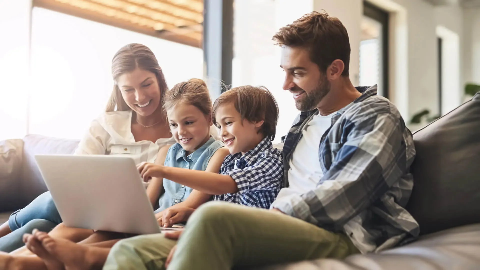 Familie sitzt auf dem Sofa mit Laptop