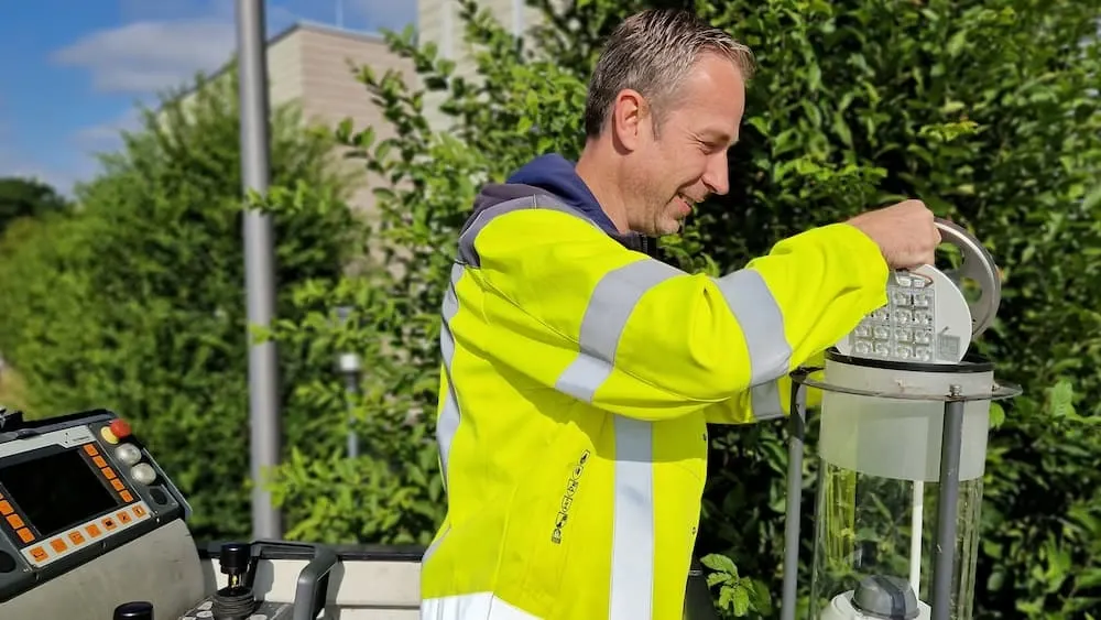 Kollege in gelber Warnjacke vor Oberleitungswagen
