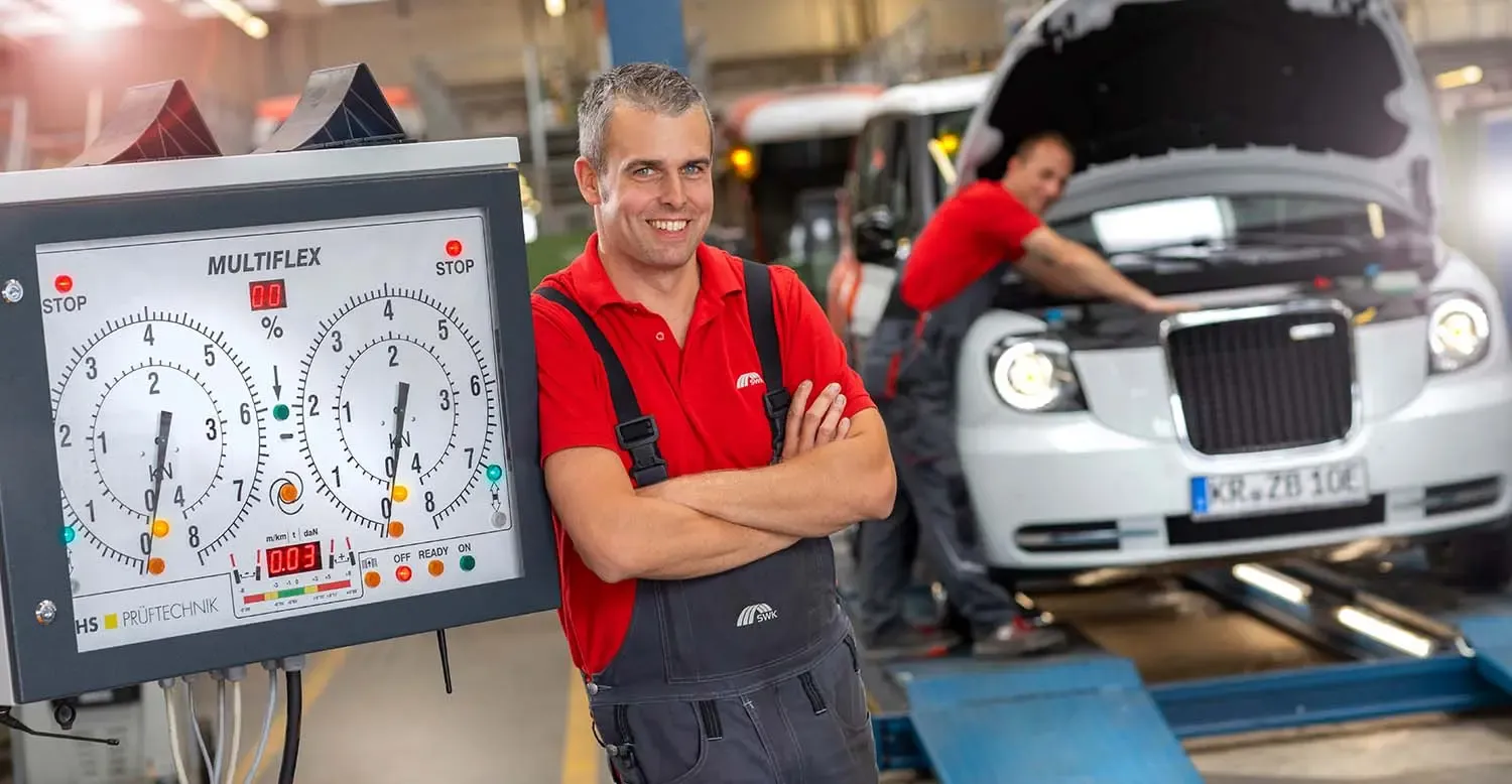 Mitarbeiter in der Fahrzeugwerkstatt lehnt an Reifendruckmessgerät