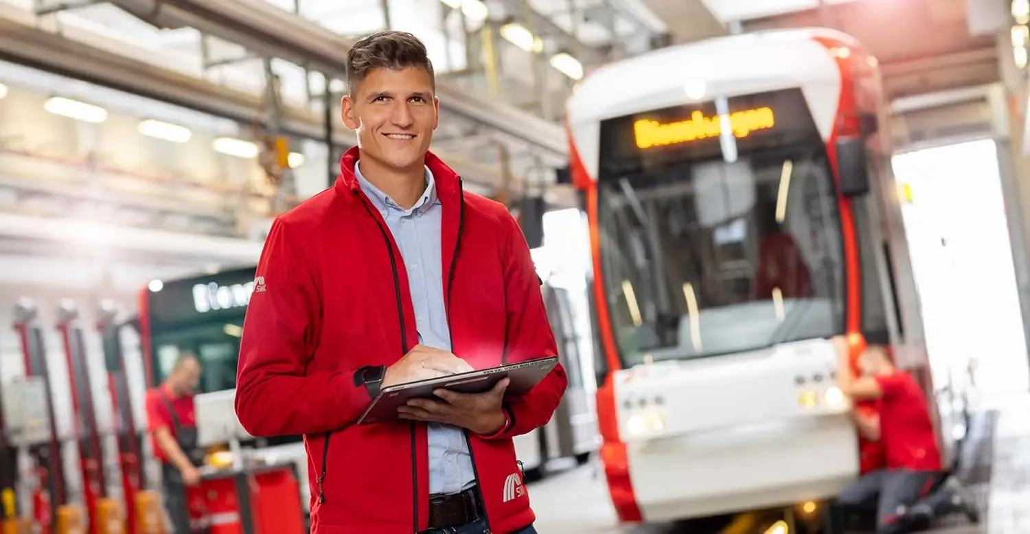 Mitarbeiter Fahrzeugwerkstatt steht mit Tablet in der Hand vor der Bahn
