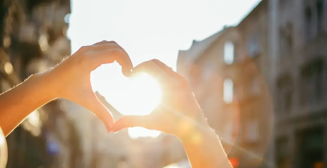 Sonne strahlt durch eine Hand zu einem Herz geformt