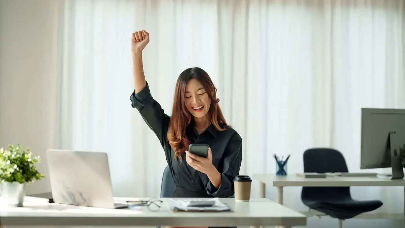 Frau checkt ihre Preise für den dynamischen Stromtarif der SWK und streckt die Faust nach oben