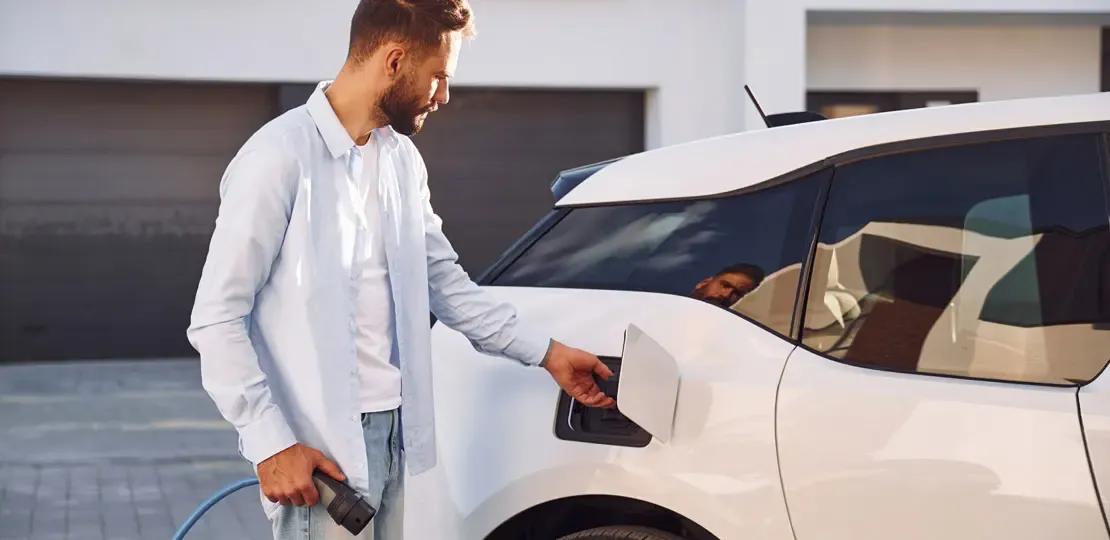 Junger Mann lädt Auto an Ladestation