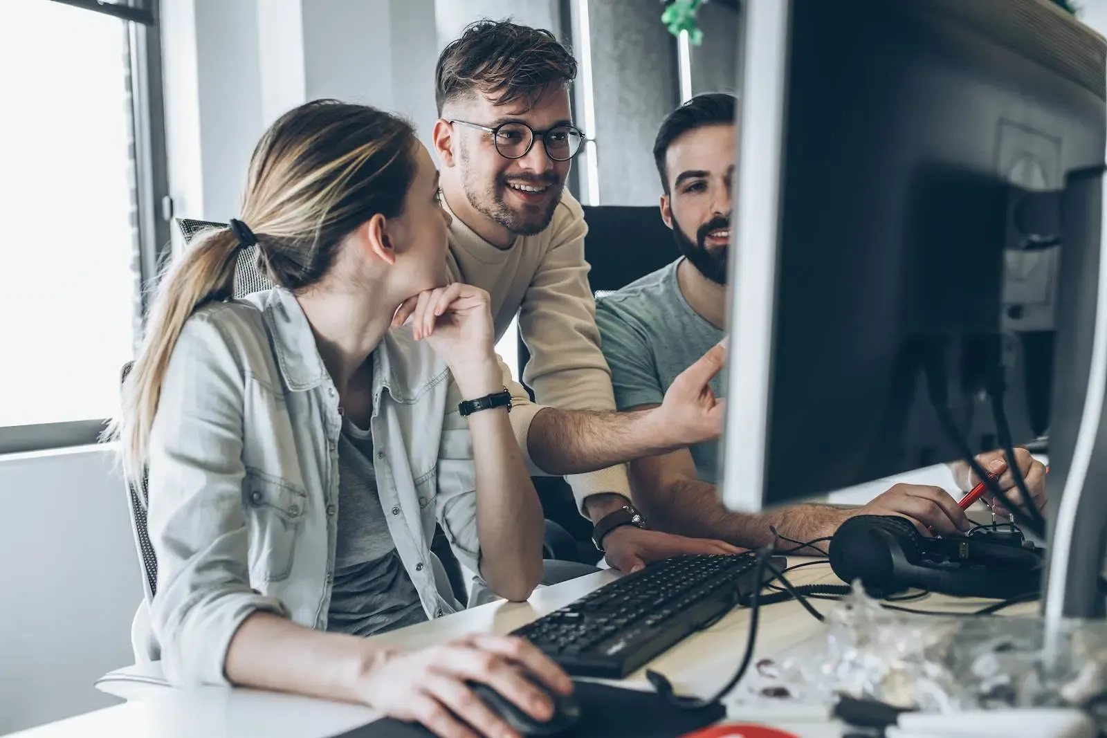 Mitarbeitende in der SWK IT sitzen am PC und diskutieren