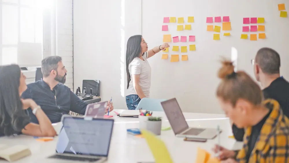 Meeting mit mehreren Personen und Postits auf dem Whiteboard