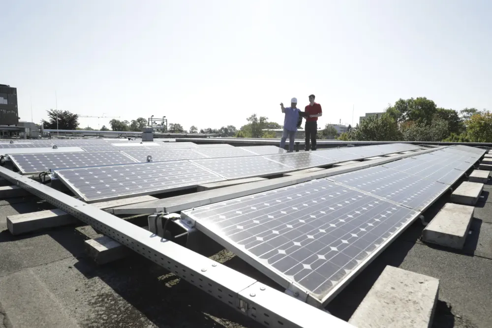 Zwei Personen auf einen Dach, das mit PV Anlage