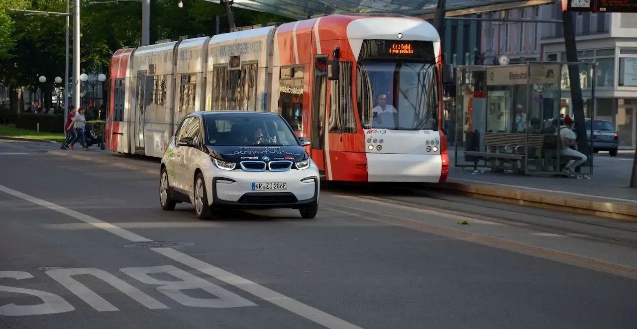 Straßenbahn und CarSharing Auto fahren nebeneinander
