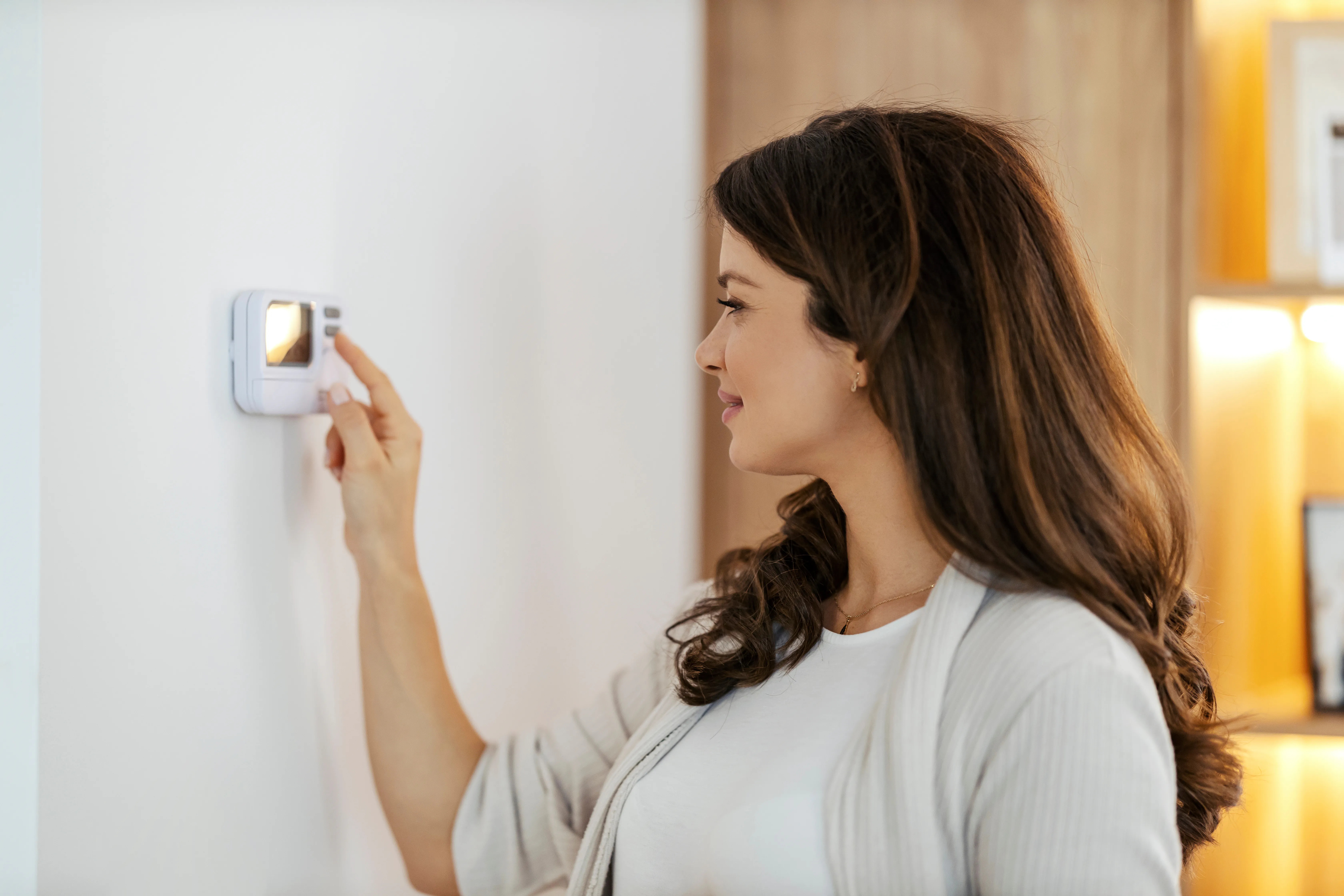 Frau in ihrem Haus bedient Thermostat