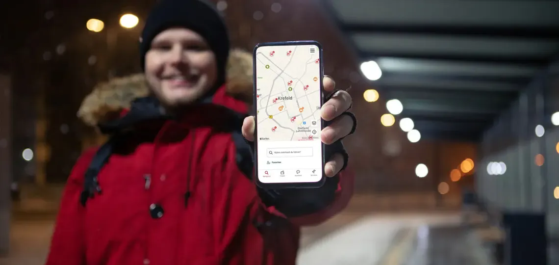 Kunde an Haltestellte hält die SWK App in die Kamera