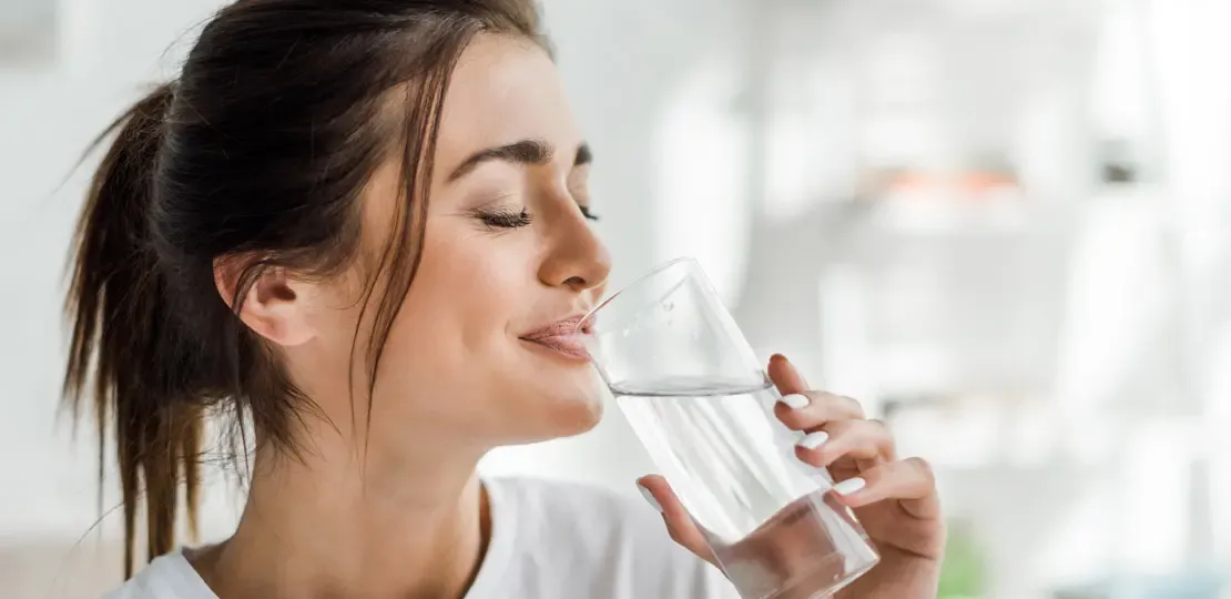 Frau trinkt Wasser aus einem Glas