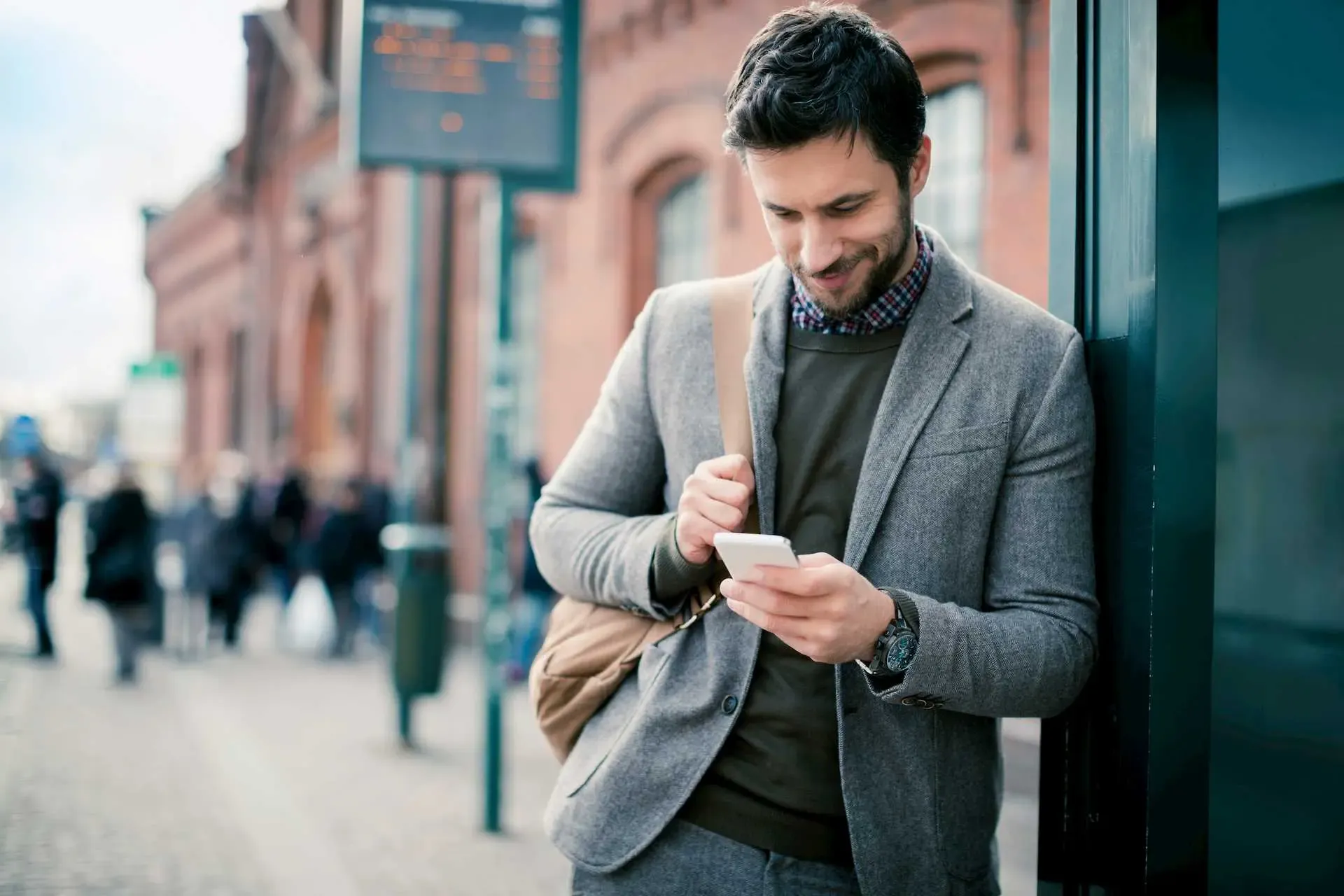 Mann steht an Bushaltestelle mit Smartphone in der Hand
