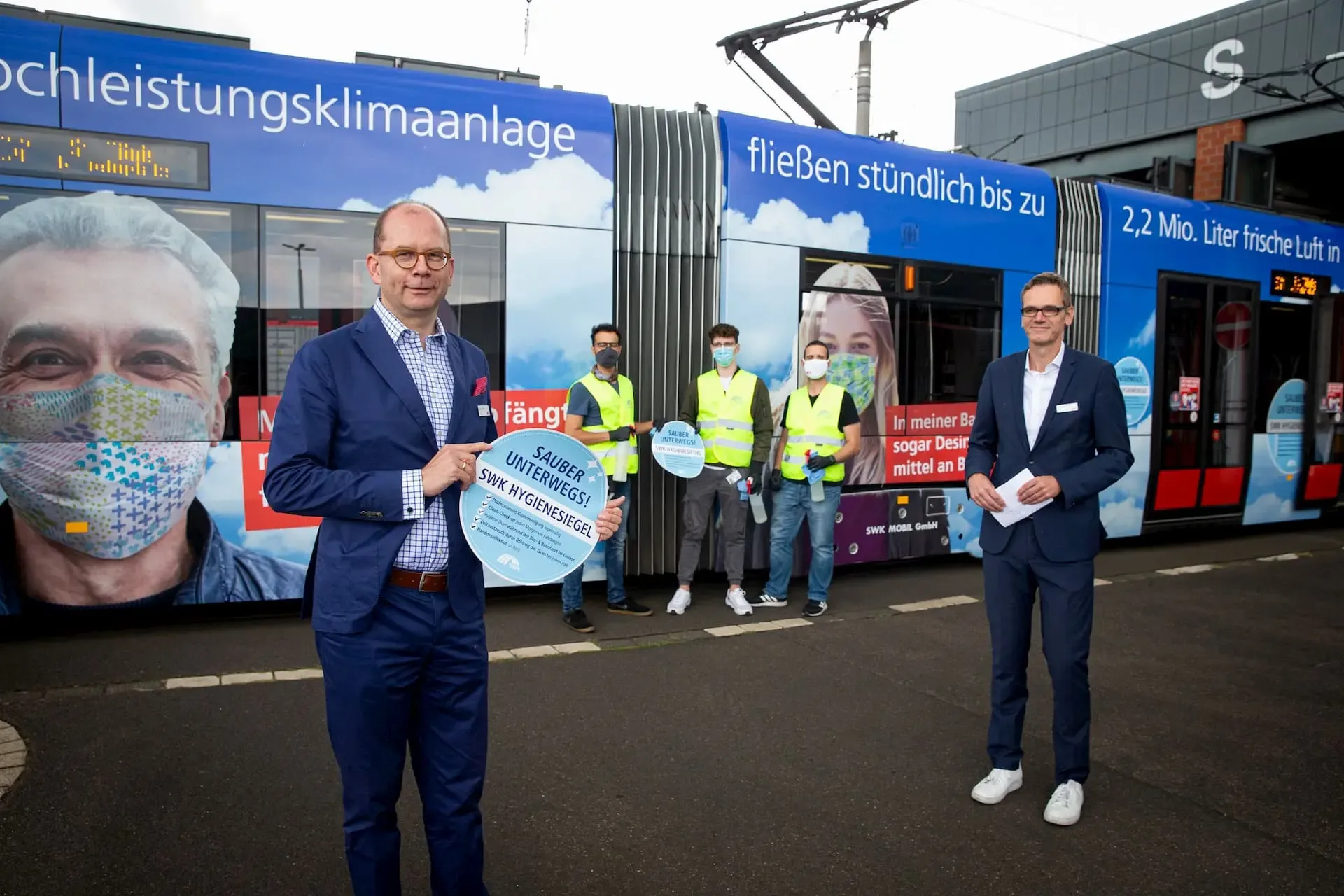Carsten Liedtke und Guido Stilling mit Hygienekonzept Aufkleber vor einer Straßenbahn der SWK Mobil