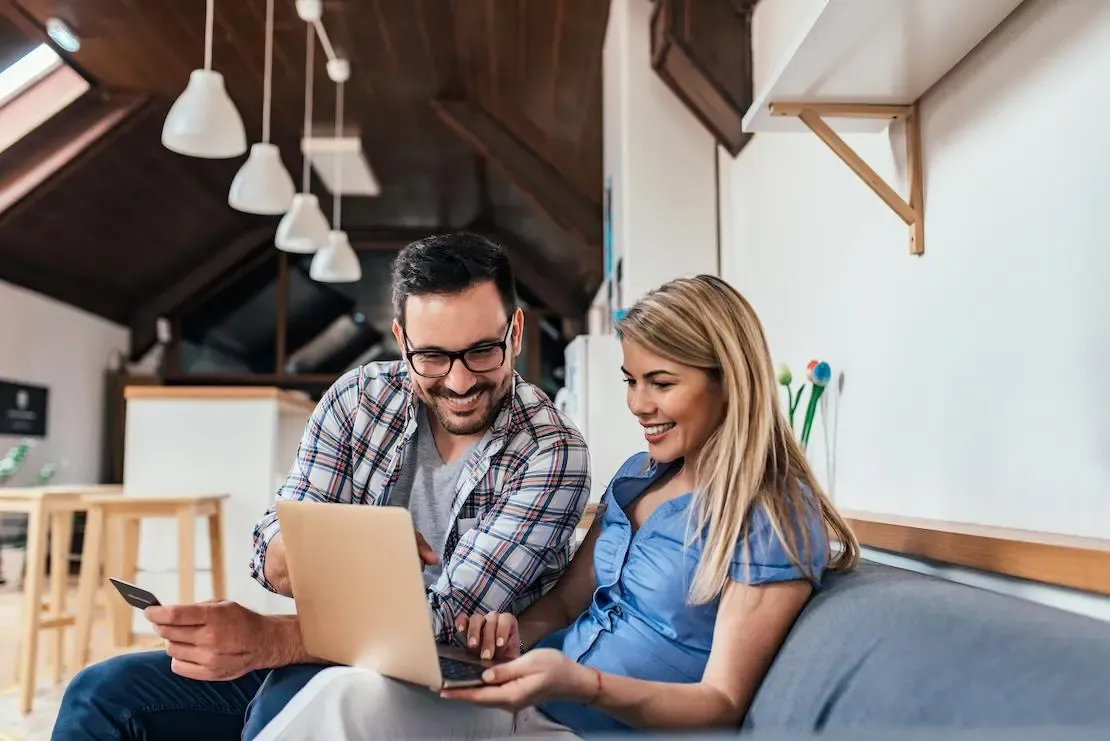 Mann und Frau sitzen nebeneinander und schauen auf einen Laptop