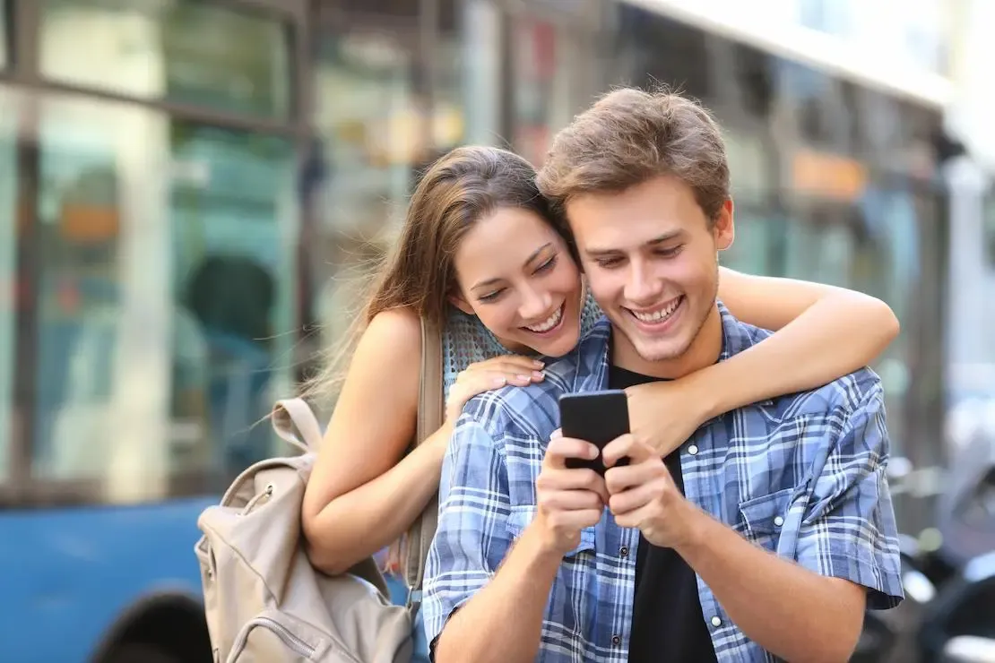 Frau umarmt Mann und schauen auf das Smartphone