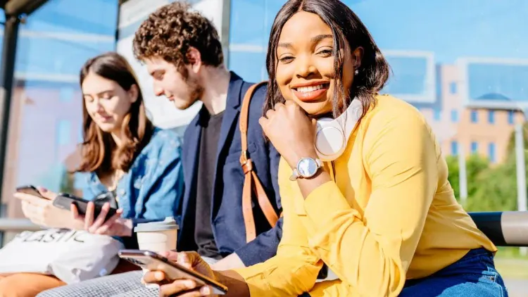 Freunde sitzen nebeneinander und eine Person schaut in die Kamera