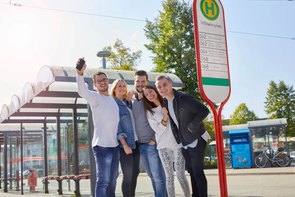 Gruppe steht an einer Bushaltestelle