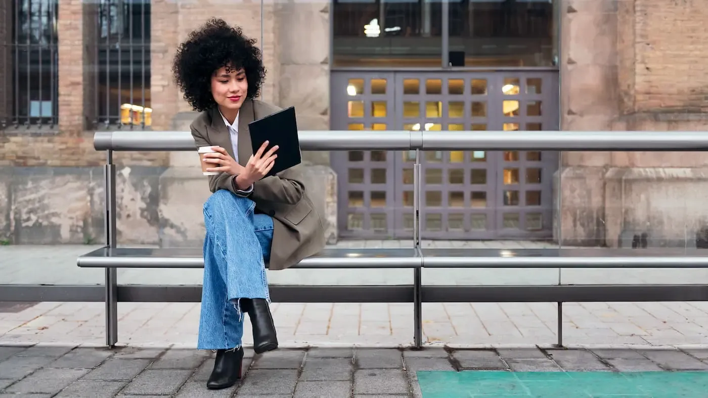 Frau an der Haltestelle mit Tablet