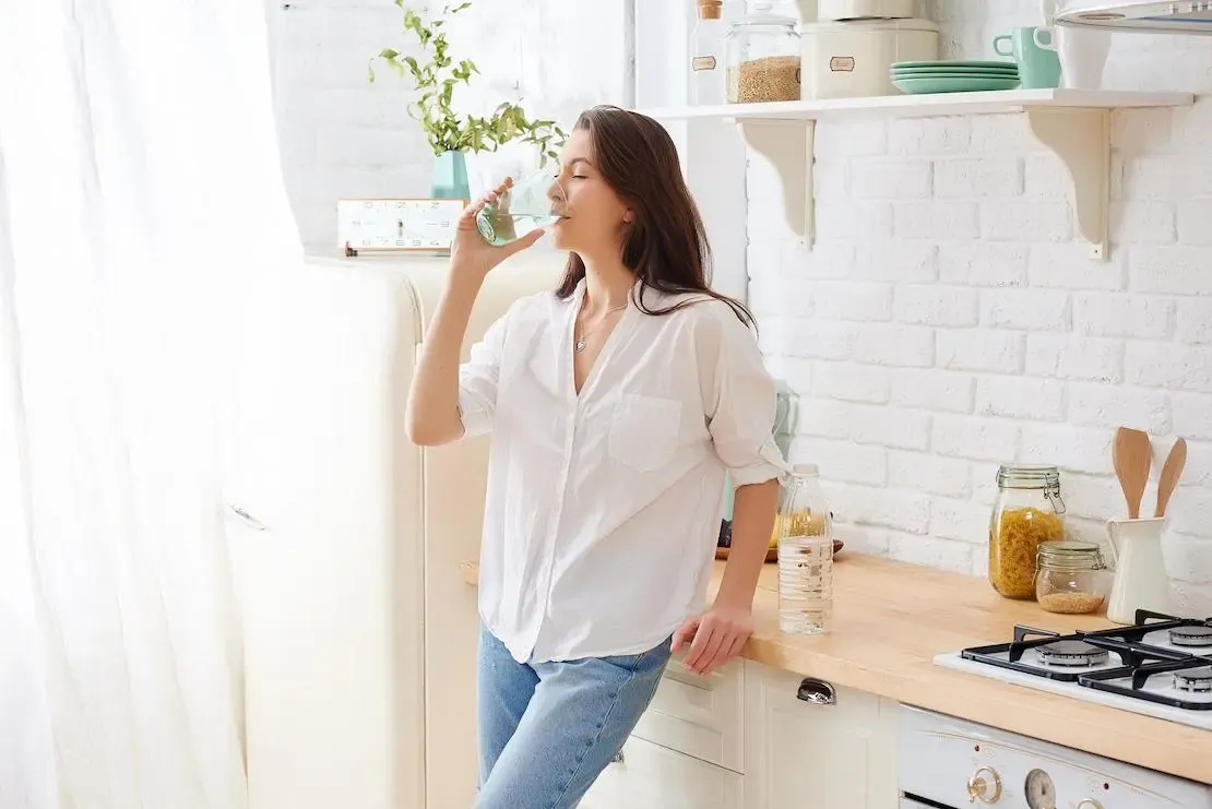 Frau trinkt Wasser aus einem Glas