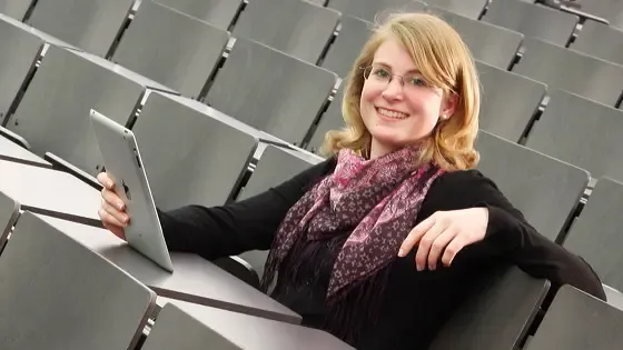 Junge Frau mit Tablet in der Hand sitzt in Vorlesungssaal