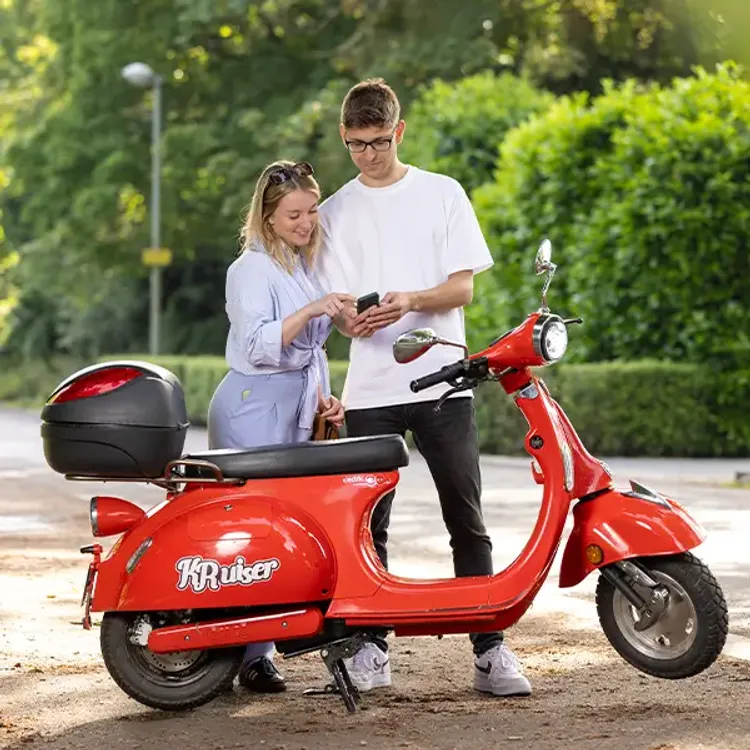 Junges Paar steht gemeinsam mit Smartphone am roten SWK KRuiser