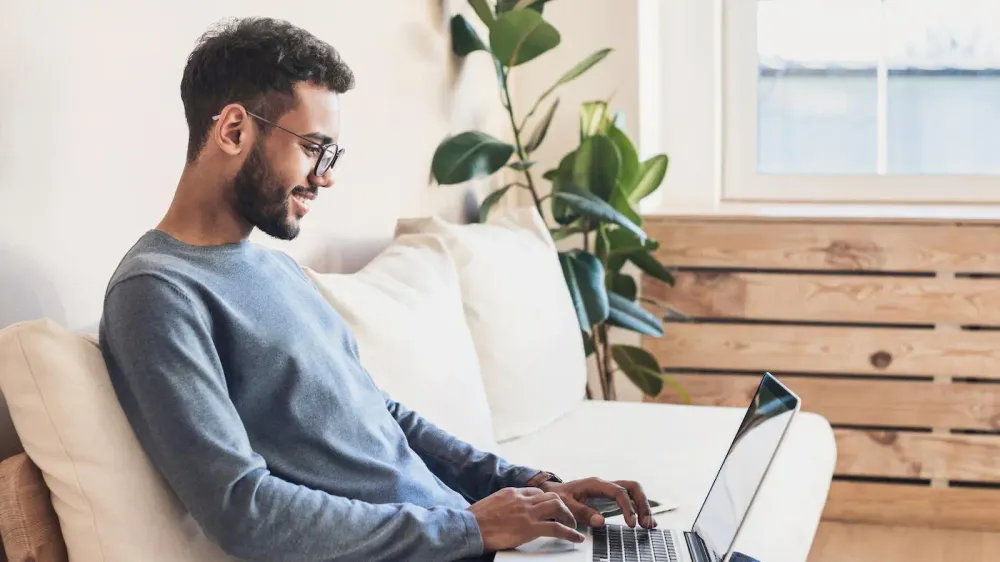 Mann sitzt mit Laptop auf dem Sofa