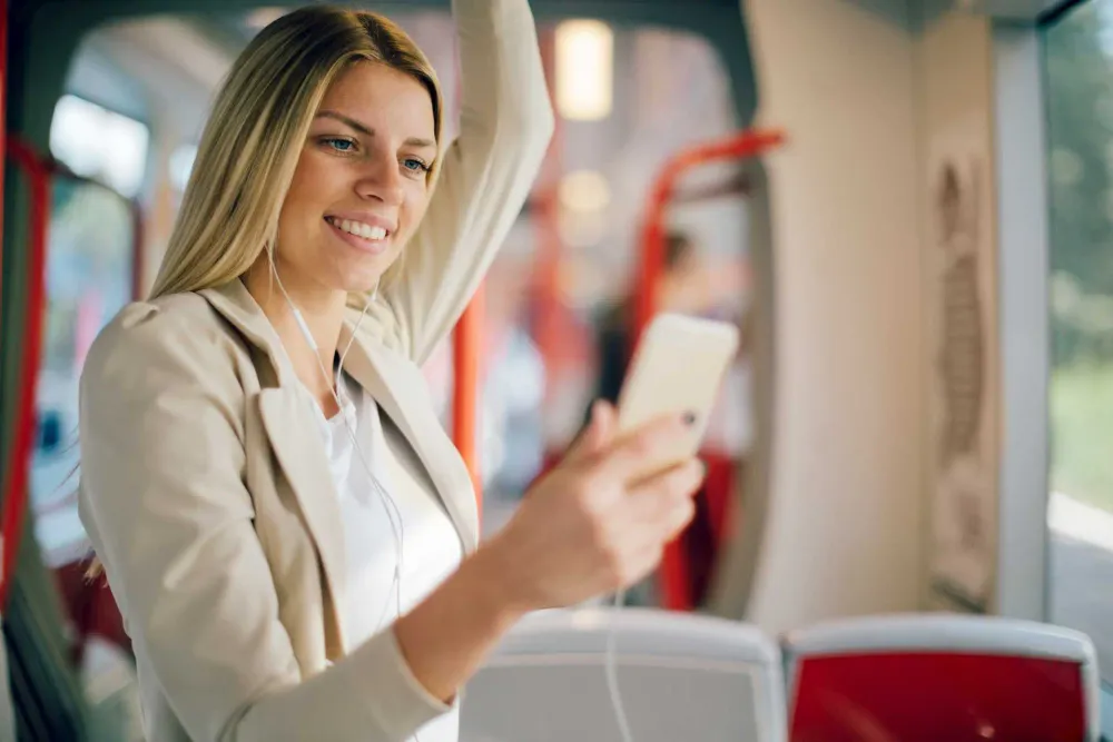 Junge Frau steht mit Smartphone in der Bahn