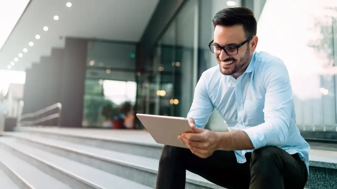 Mann mit Tablet sitzt auf der Treppe