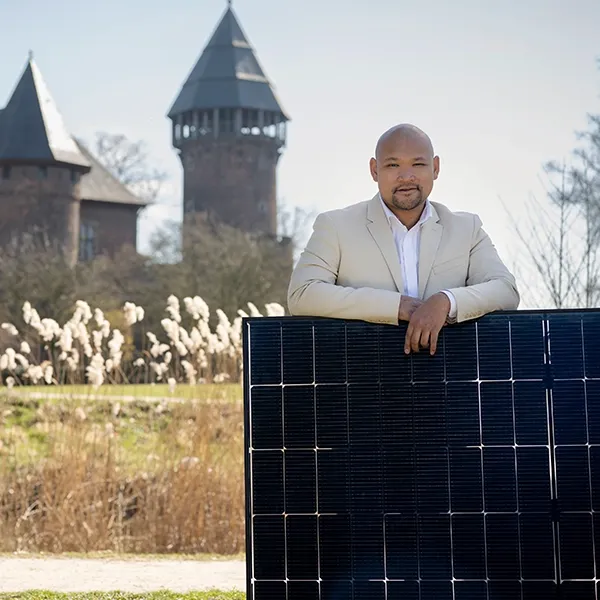 SWK Energie-Experte mit PV-Modul vor Krefelder Burg Linn