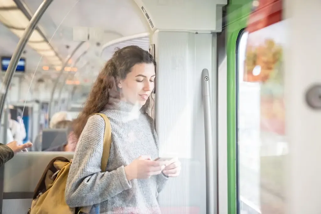 Junge Frau in der Bahn schaut auf ihr Smartphone