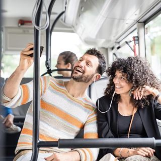Paar sitzt im Bus und macht ein Selfie